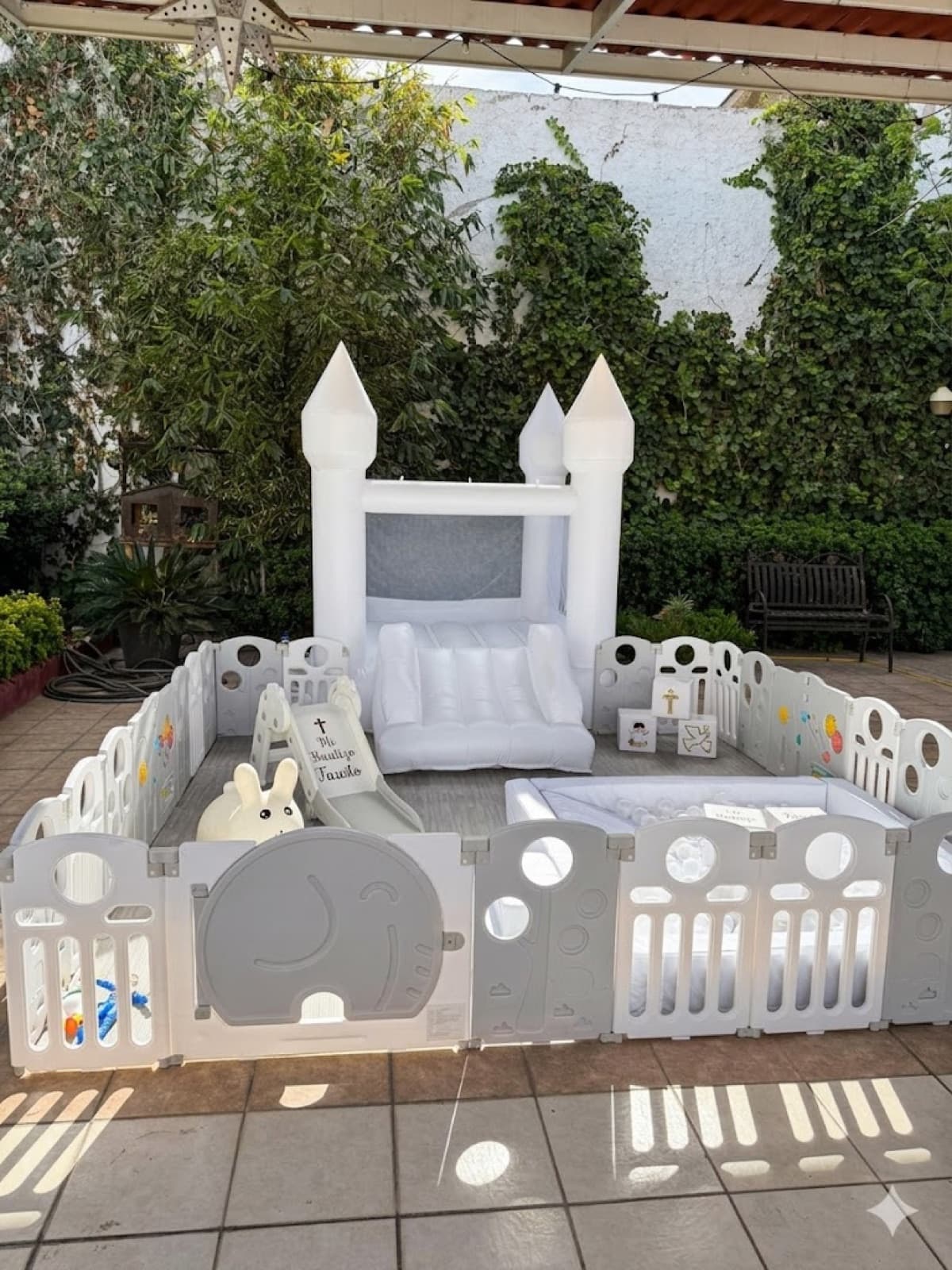 Setup completo del bautizo de Fausto bajo pergola con plantas verdes